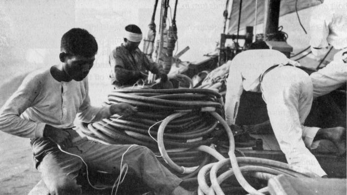 Image of men on the deck of a boat and a coiled air hose.